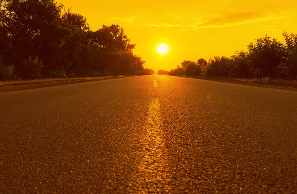 Turuncu günbatımı ve asfalt yol. yumuşak odak — Stok fotoğraf
