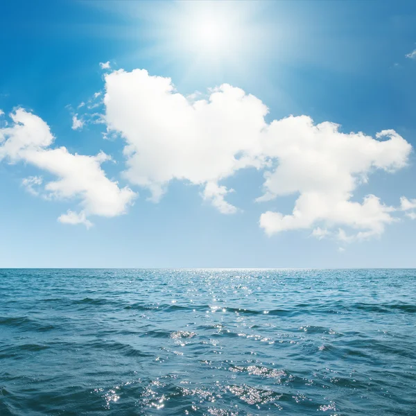 Slunce na modré obloze s mraky nad mořem — Stock fotografie