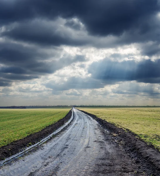 Estrada suja para o horizonte e o céu dramático — Fotografia de Stock