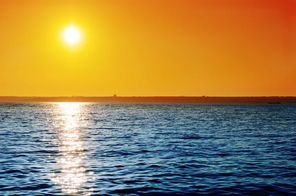Oranje hemel op zonsondergang over blauwe water — Stockfoto