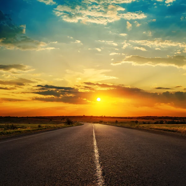 Oranje zonsondergang in wolken over asfaltweg — Stockfoto