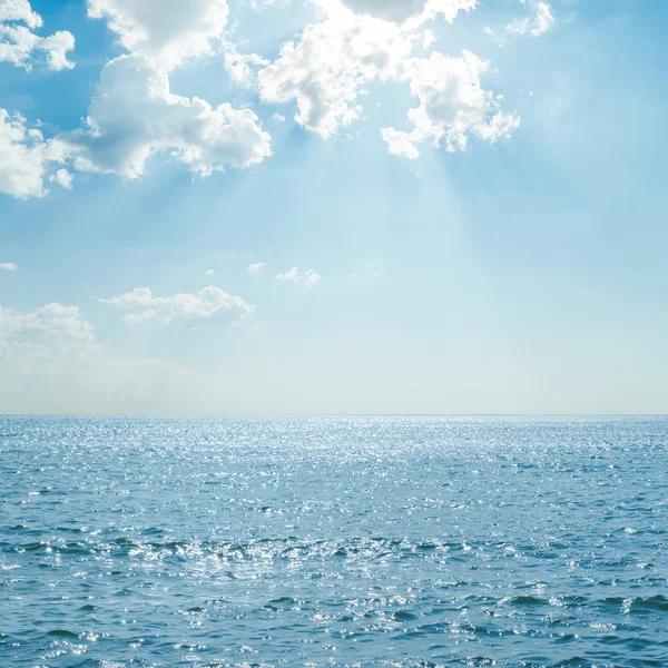 Синее море с отражениями под облака и солнце — стоковое фото