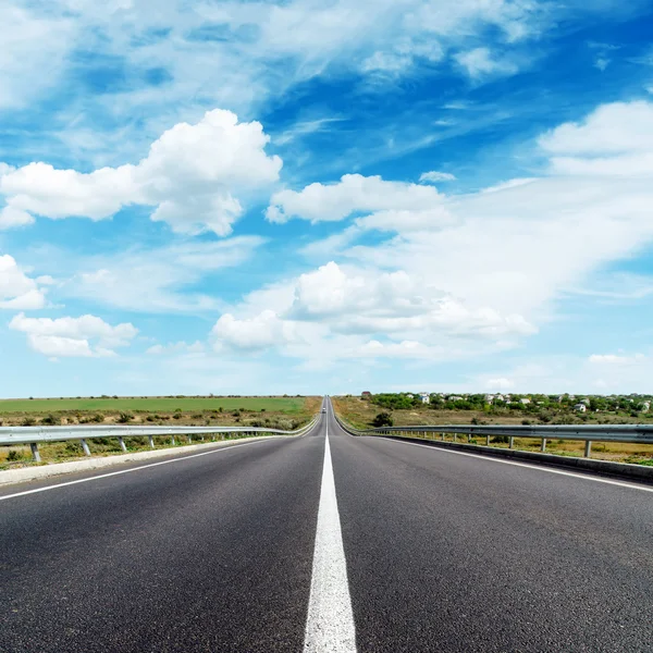 Asphalt road with central white line under cloudy sky — Stock Photo, Image