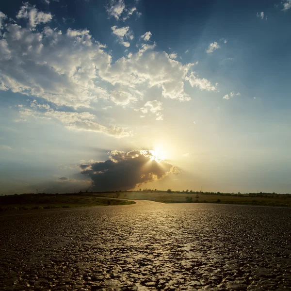 Low sun in clouds on sunset over asphalt road — Stock Photo, Image