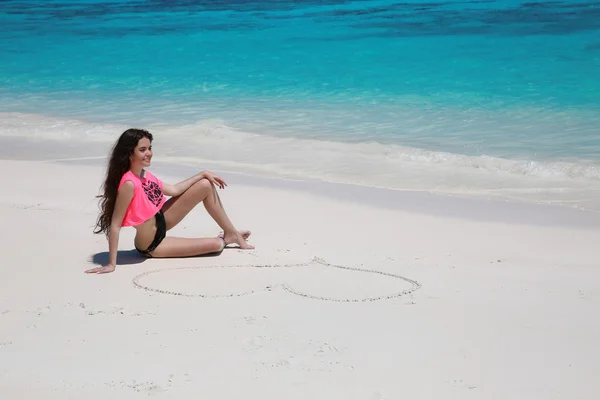 Sexy schönes Mädchen mit Herz auf Sand im schwarzen Bikini entspannt — Stockfoto