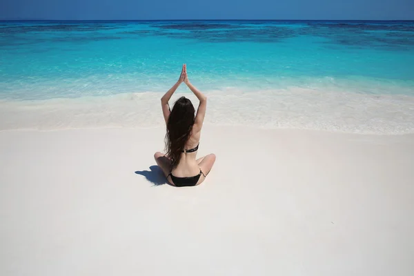 Young woman practicing yoga on the exotic beach with blue water — Φωτογραφία Αρχείου