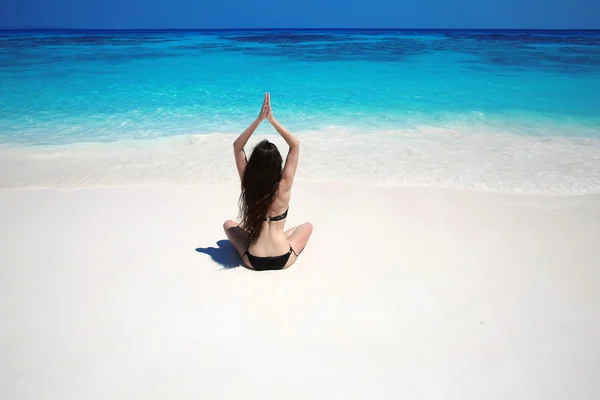 Junge Frau praktiziert Yoga am tropischen Strand mit blauem Wasser — Stockfoto