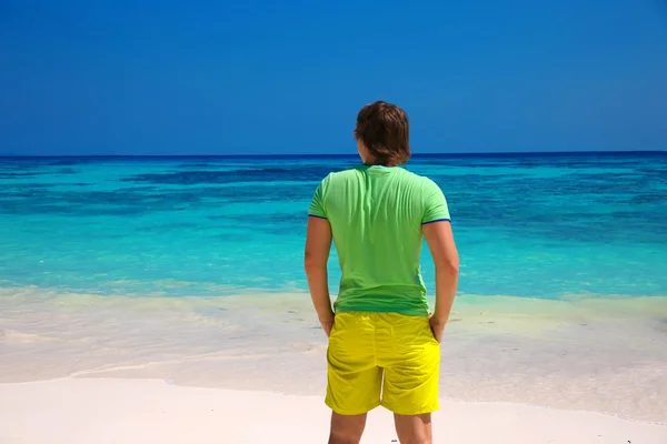 Vista trasera del hombre de negocios disfrutando de una buena vida en la playa exótica, tipo mirando a la orilla del mar, fondo de isla tropical. Concepto de viaje . — Foto de Stock