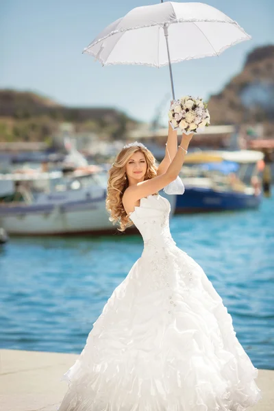 Hermosa novia en vestido de novia con paraguas blanco posando encima — Foto de Stock