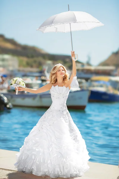 Belle mariée en robe de mariée avec parapluie blanc posant sur — Photo