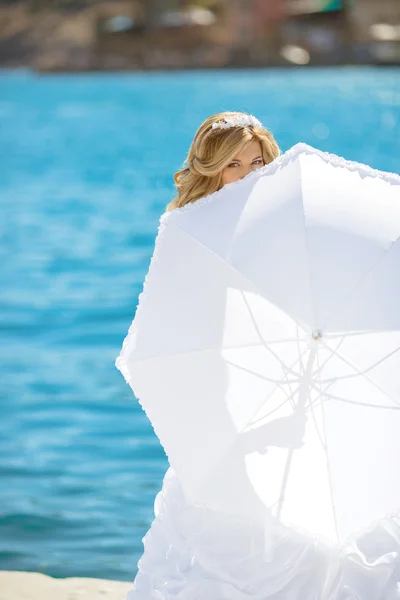 Bella sposa in abito da sposa nascosto da ombrello bianco in posa — Foto Stock