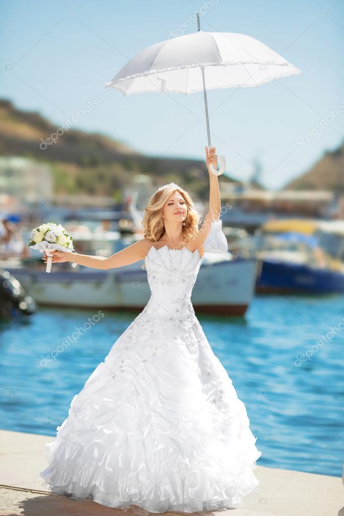 Beautiful bride in wedding dress with white umbrella posing over