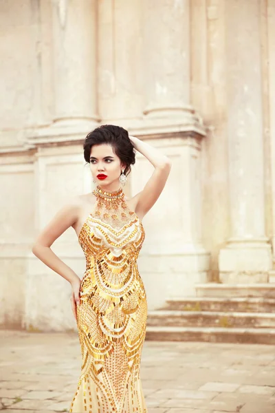 Modelo de moda en vestido de oro. Hermosa morena sexy en elegante —  Fotos de Stock
