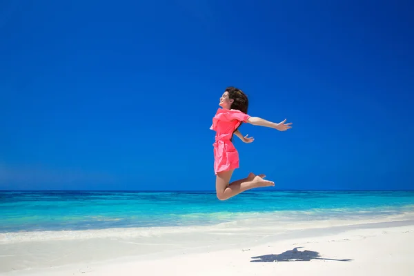 Le plaisir. Heureuse femme libre sautant par-dessus la mer et le ciel bleu, brune — Photo