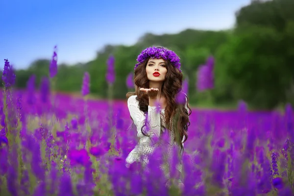 Beautidul brünette teen girl sendet einen Luftkuss über wilde Blumen — Stockfoto