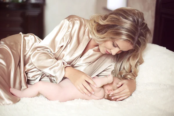 Mãe bonita bebê calmo deitado na cama. Mamãe abraçando sua filha — Fotografia de Stock