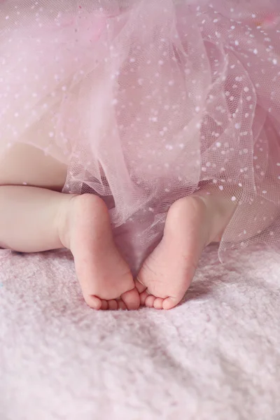 Close-up van het meisje van de voeten van de pasgeboren baby tegen zachte roze deken rug — Stockfoto