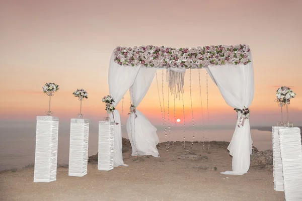 Bruiloft boog met bloemstuk met witte gordijn op sunse — Stockfoto