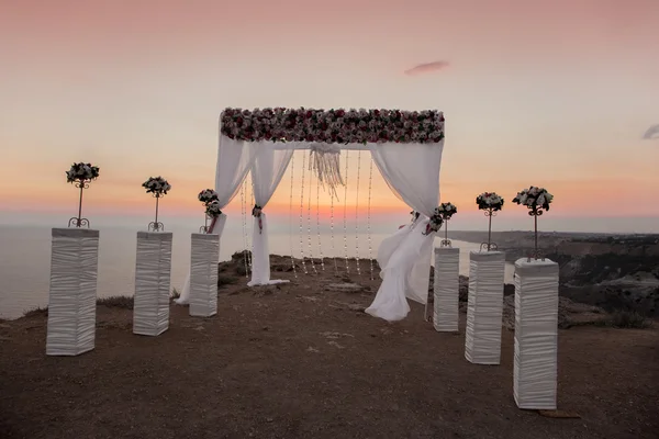 Svatební oblouk s aranžování květin s bílým závěsem na sunse — Stock fotografie