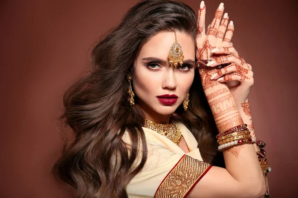 多毛的头发 一个有着印第安珠宝的漂亮女人的画像 年轻的黑发模特配上传统的印度金黄色比约特儿套装 Mehendi Henna手头上的油画 — 图库照片