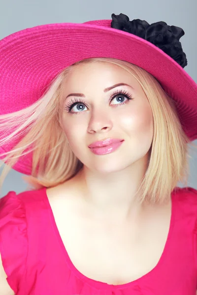 Beautiful blond woman with blowing hair in pink hat. Makeup, smi — Stock Photo, Image