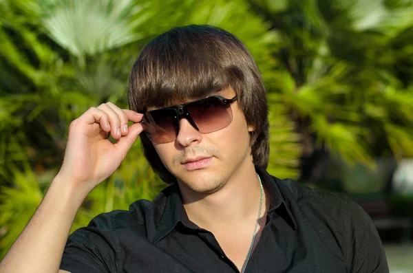 Hombre guapo de moda con gafas de sol sobre la palma, al aire libre por —  Fotos de Stock