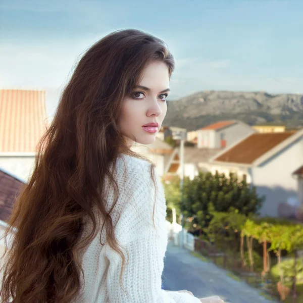 Aantrekkelijke brunette meisje met gezond lange golvende haar staande op — Stockfoto