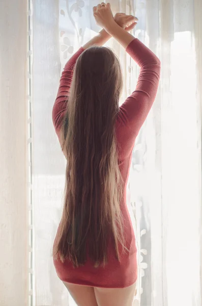 Cabelo comprido. Sexy modelo menina posando pela janela . — Fotografia de Stock