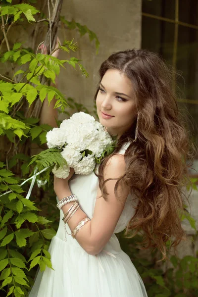 Mooie lachende bruid met bruiloft boeket van bloemen in het park. — Stockfoto