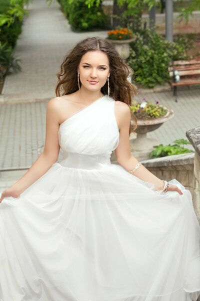 Привлекательная невеста с длинными волнистыми волосами в свадебном платье с объемом
