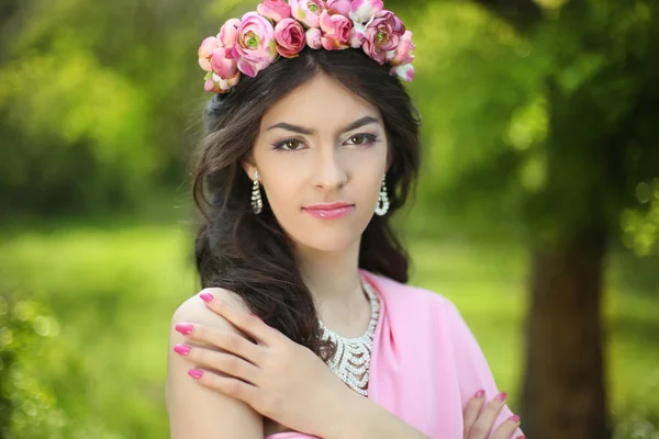 Brunett tjej med blomma halsband i grönt arkiverat klädd i rosa — Stockfoto