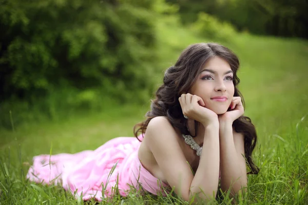 Attractive young teen girl with makeup wearing in pink dress lyi — Stock Photo, Image