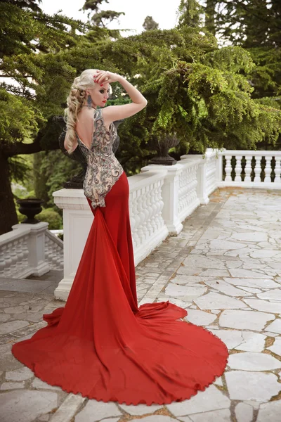 Elegáns szőke nő divatmodell hosszú vonat a piros ruha — Stock Fotó