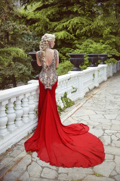 Moda elegante modello donna bionda in abito rosso con lungo treno di — Foto Stock