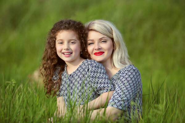 Smiling mother and funny daughter in green grass field. outdoor 