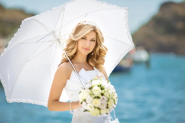 Mooie bruid meisje in bruiloft jurk met witte paraplu en bo — Stockfoto
