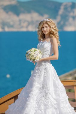Beautiful blond bride in wedding dress with bouquet of flowers o