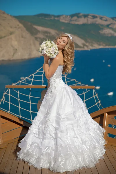 Beautiful smiling bride in wedding dress with bouquet of flowers — Stok fotoğraf