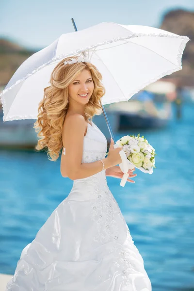 Schönes lächelndes Brautmädchen im Brautkleid mit weißem Regenschirm — Stockfoto