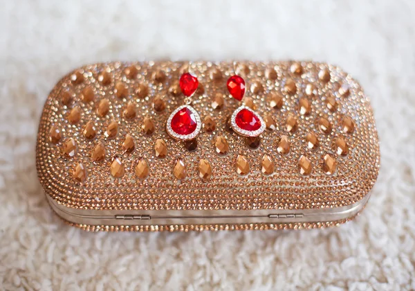 Brincos de moda estilo jóias vermelhas com diamantes na bolsa dourada — Fotografia de Stock