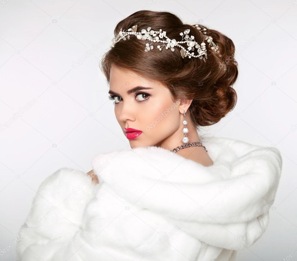 Elegant woman in white fur coat. Wedding Hairstyle. Beautiful fa