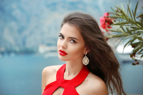 Menina bonita com lábios vermelhos, cabelo ondulado longo e brinco de moda — Fotografia de Stock