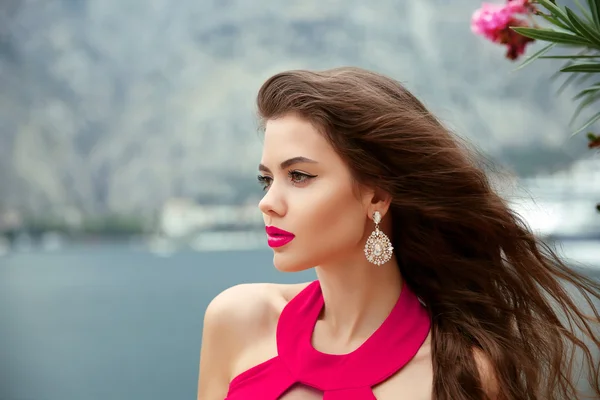 Beautiful girl with long wavy hair, red lips and fashion earring — Stockfoto