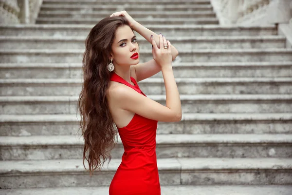 髪の長い健康的なポジで赤いドレスの美しいブルネットの少女 — ストック写真