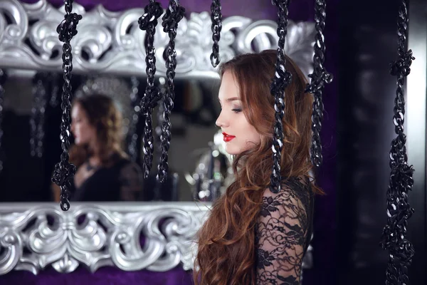 Beautiful brunette woman by mirror with silver baroque decorativ — 스톡 사진