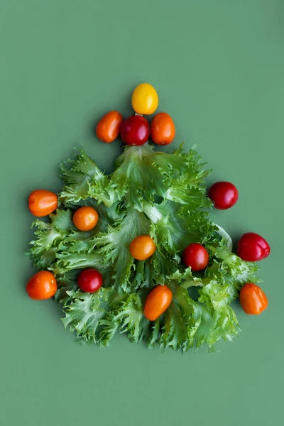 Yeni yıl tatili için düşük kalorili diyet konsepti. Sebzeli Noel ağacı salatası, marul yaprağı ve vişneli domates. Bebek tabağı komik basit masa dekorasyonu. Sağlıklı Vitamin zengini akşam yemeği