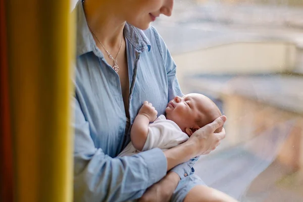 Anne çocuğu sallıyor. Annesinin kollarında uyuyan bir bebeğin portresi. Şefkatli sevgi. Annelik. Ninni söylüyor. Bebek sağlıklı uyku. Genç anne. Küçük tatlı bebek. Gerçek yaşam tarzı
