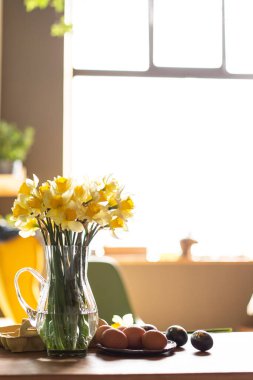 Güzel bir Paskalya şenliği. Odada hayat var. Cam vazoda bir buket nergis ve boyalı yumurtalar masanın üzerinde. Bahar havası. Oturma odasının içi. Çiçekler sarı narsisli bahar çiçeği