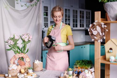 Güzel, genç, modern ev hanımı mutfakta yemek yapıyor. Karıştırıcıyla yemek yapan bir kadının portresi. Paskalya yemeği hazırlığı. Şekerci 'nin işyeri. Hobi olarak rahatla. Dijital detoks. önlük