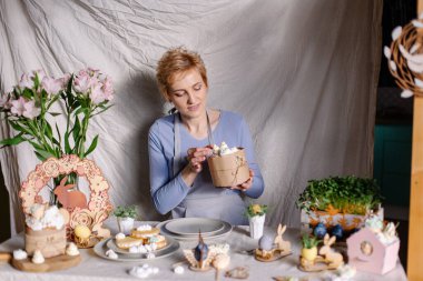 Güzel, modern genç bir kadın Paskalya pastasını kremayla süslüyor. Pasta şefi kek pişirmeye çalışıyor. Saf pozitif şenlik atmosferi. Annem Paskalya için ev yapımı ikramlar hazırlıyor. Mavi. Yaşam biçimi